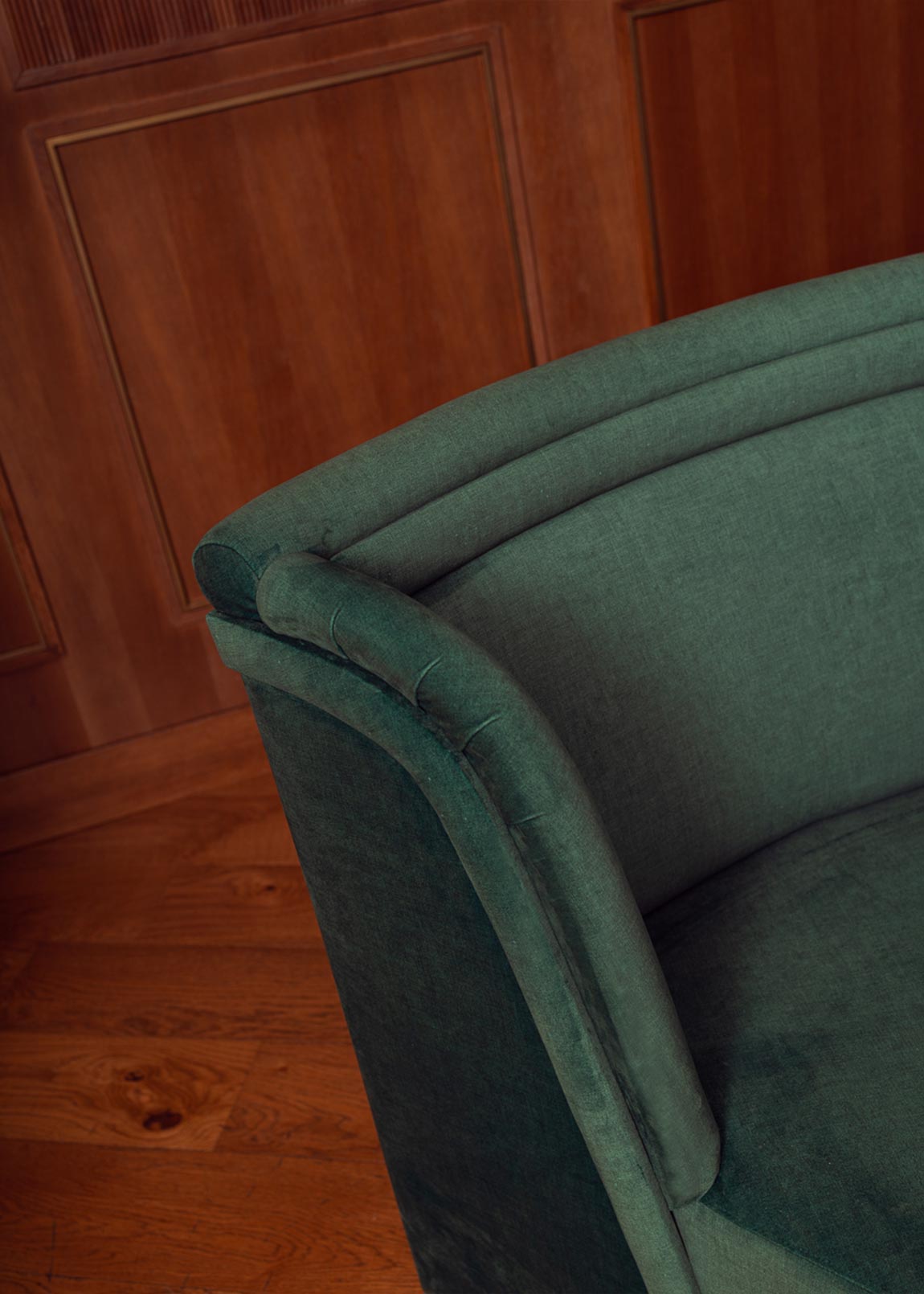 Banco curvado tapizado en terciopelo verde con patas de madera