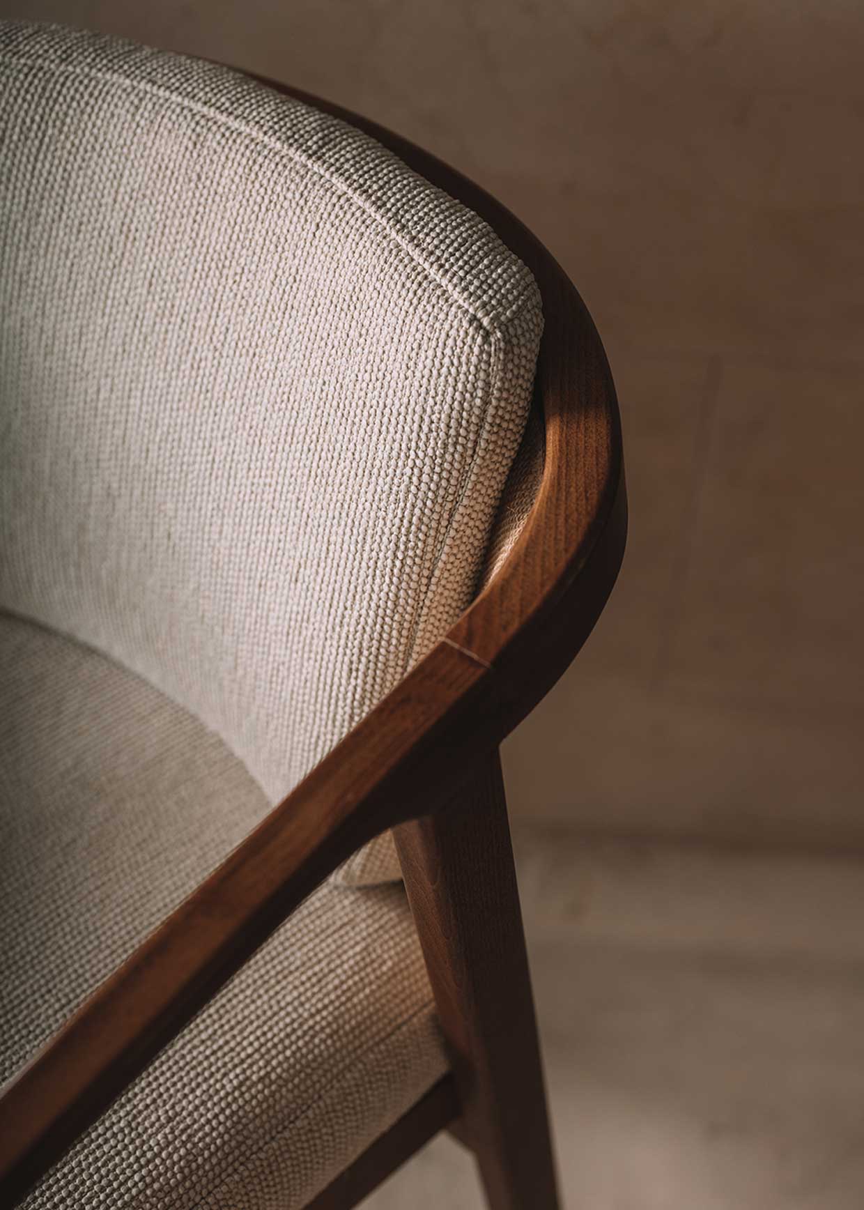 Silla de madera de haya con reposabrazos tapizada con una tela con textura en color beige