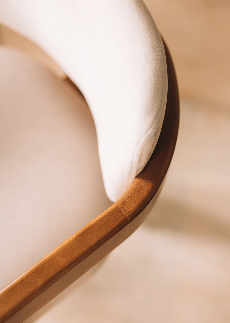 Silla de madera de haya con reposabrazos tapizada en terciopelo beige.