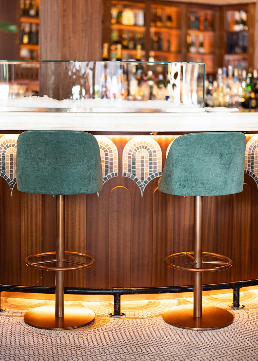 Taburete tapizado con estructura de hierro acabado en oro rosa.