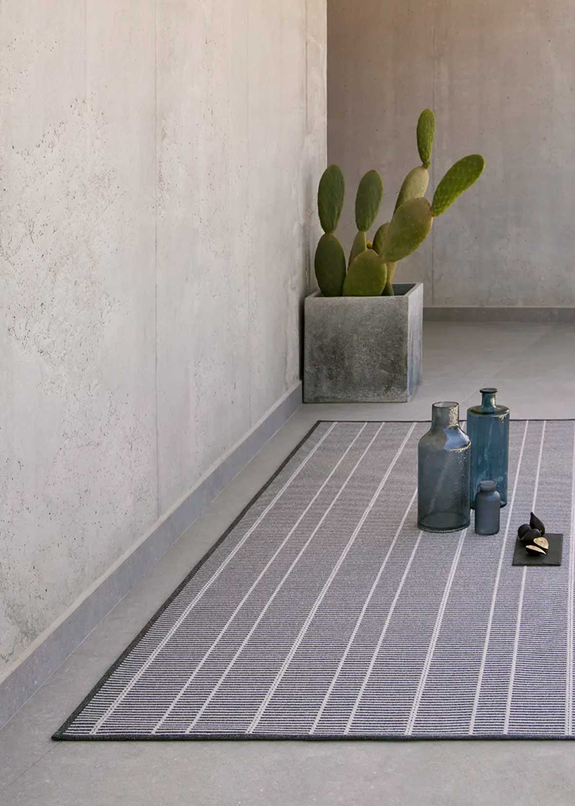 Alfombra fabricada en PET a partir de botellas de plástico recicladas de color gris azulado en telar wilton de tejido plano.