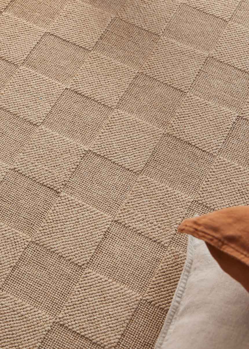 Alfombra fabricada con lana de color camel en telar wilton con superficie en bucle con saltillo.
