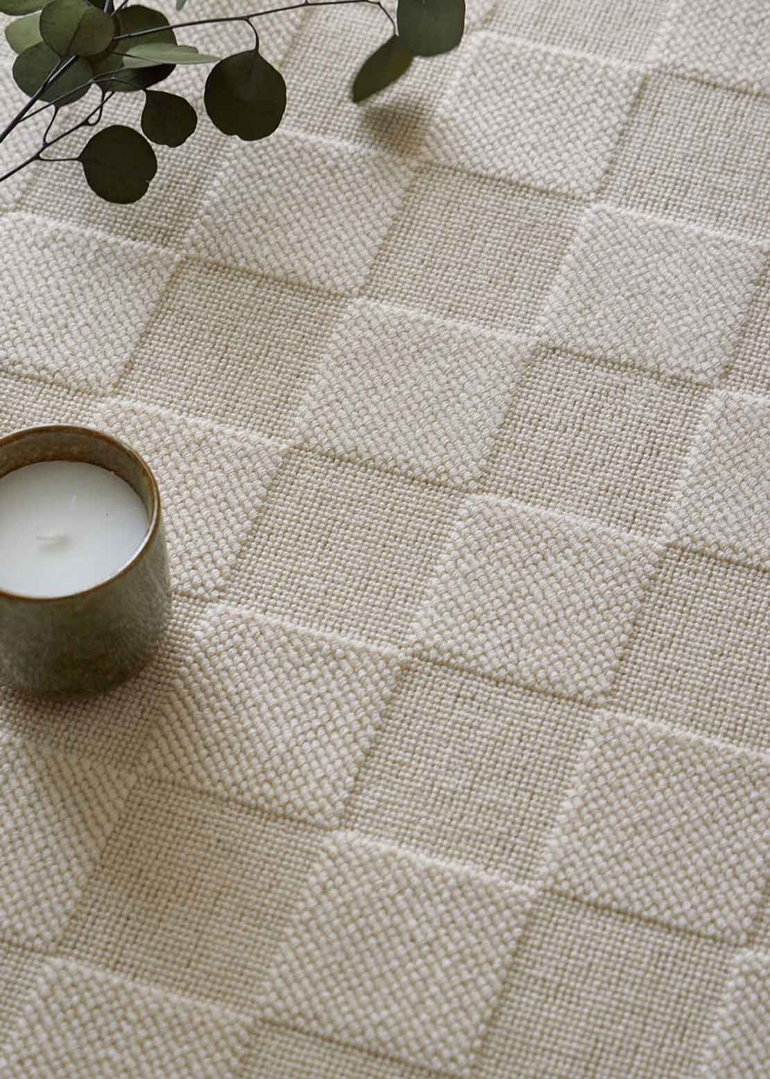 Alfombra fabricada con lana de color crema en telar wilton con superficie en bucle con saltillo.