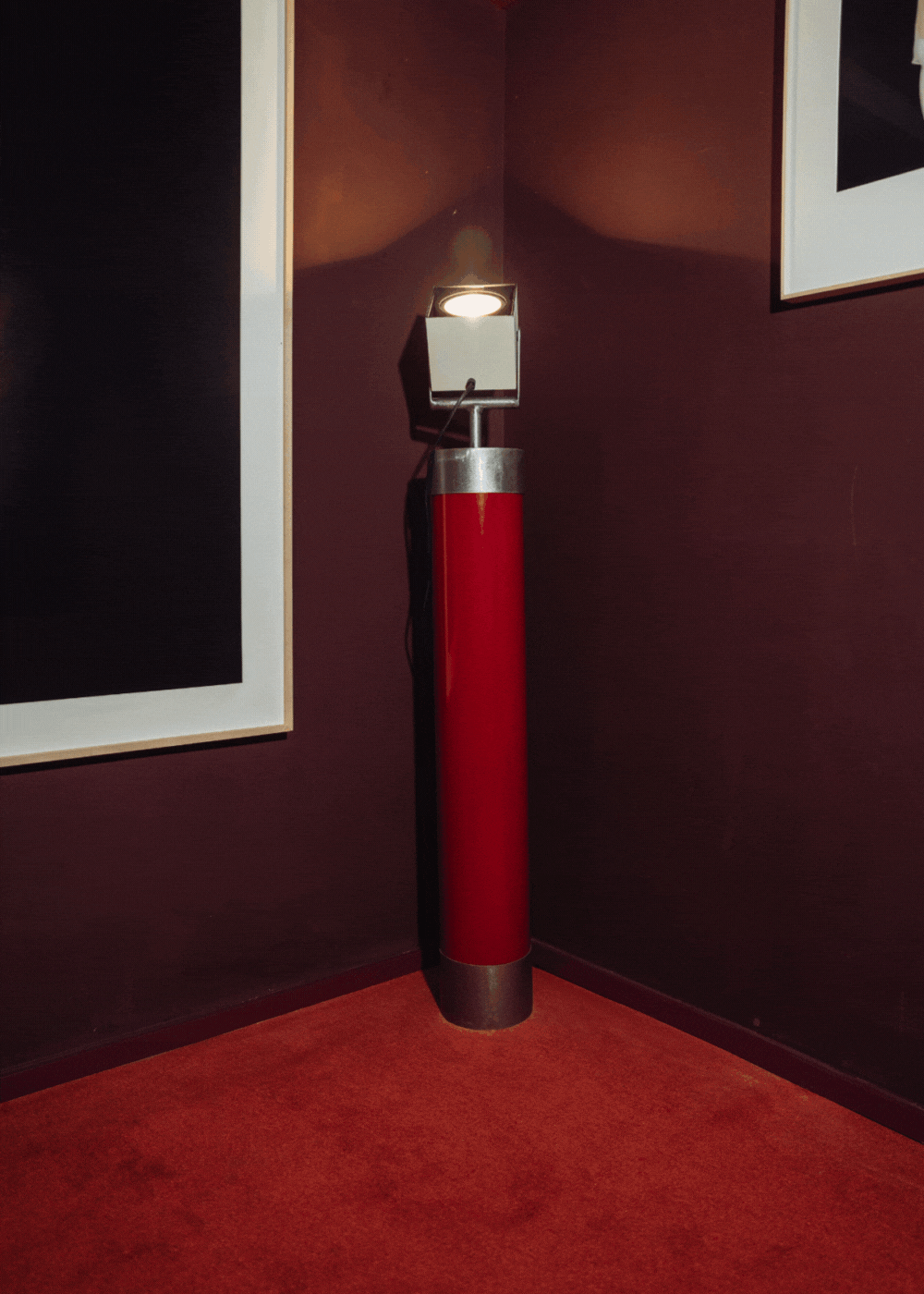 Foco orientable de pie de estilo industrial con soporte de acero lacado en rojo. Está diseñado para ir anclado al suelo.