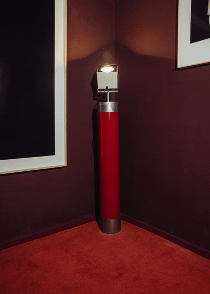 Foco orientable de pie de estilo industrial con soporte de acero lacado en rojo. Está diseñado para ir anclado al suelo.