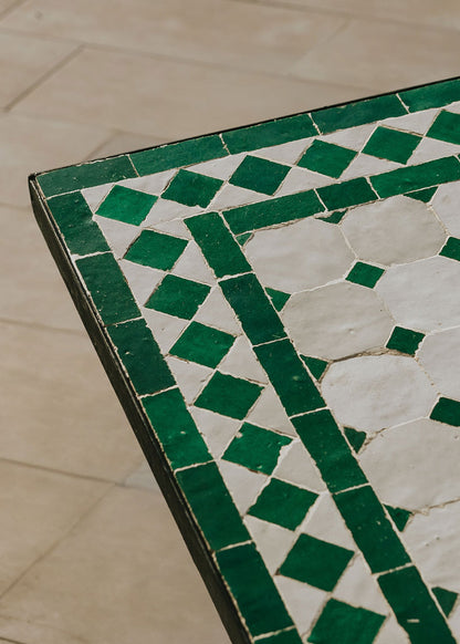 Mesa de azulejos exterior cuadrada con estructura de hierro forjado acabado en negro.