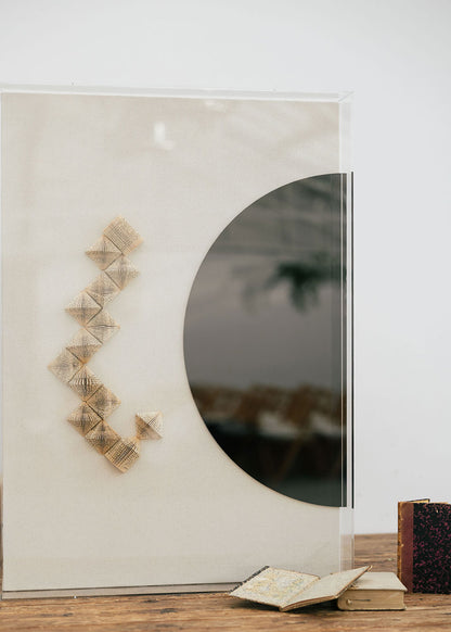 Escultura de pared en dos piezas forradas en lino rústico con cajas de metacrilato transparente. Está formada por una serie de libros plegados y formas geométricas en metacrilato.