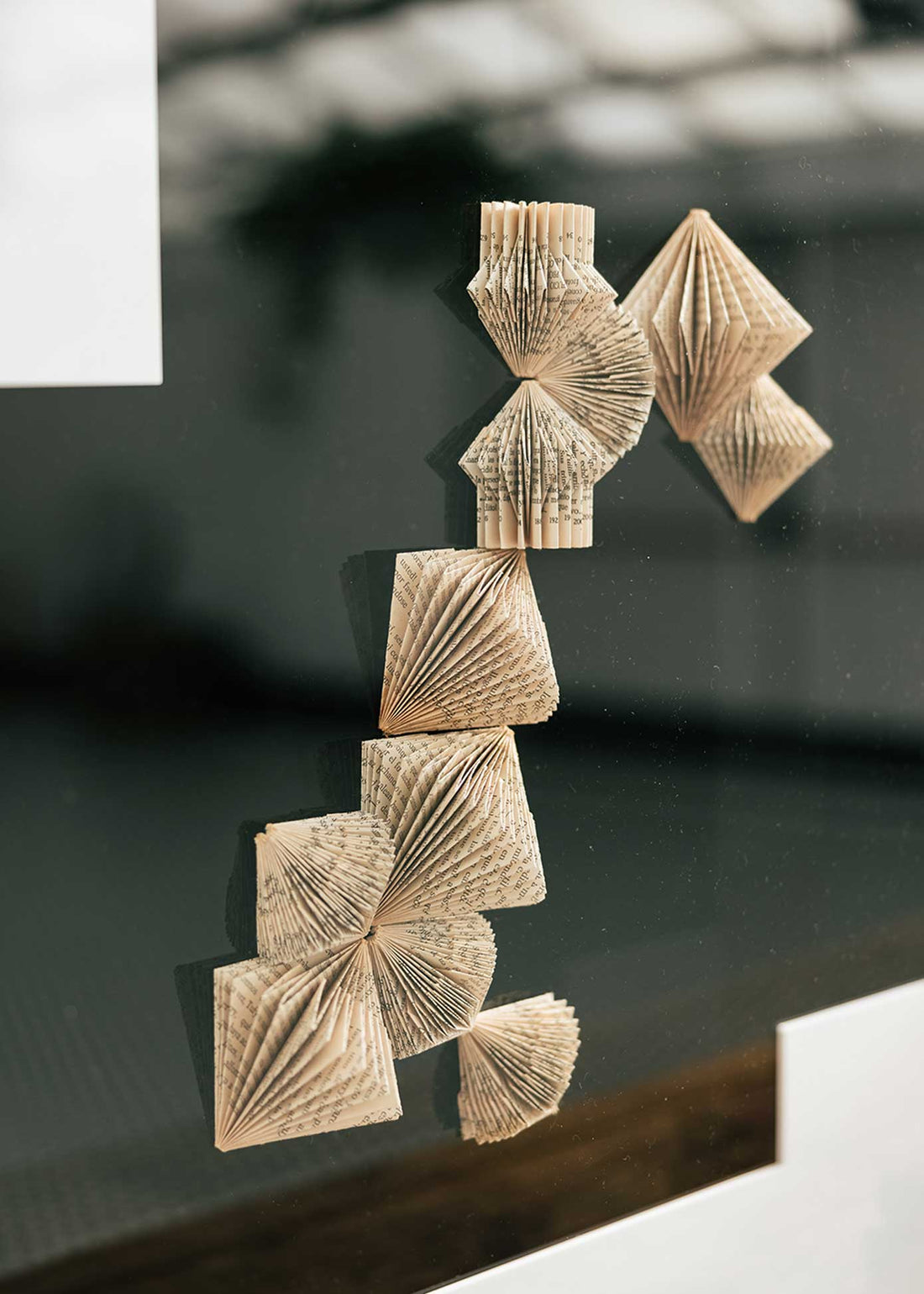 Escultura de pared forrada en metacrilato negro y blanco con caja de metacrilato transparente y serie de libros plegados.
