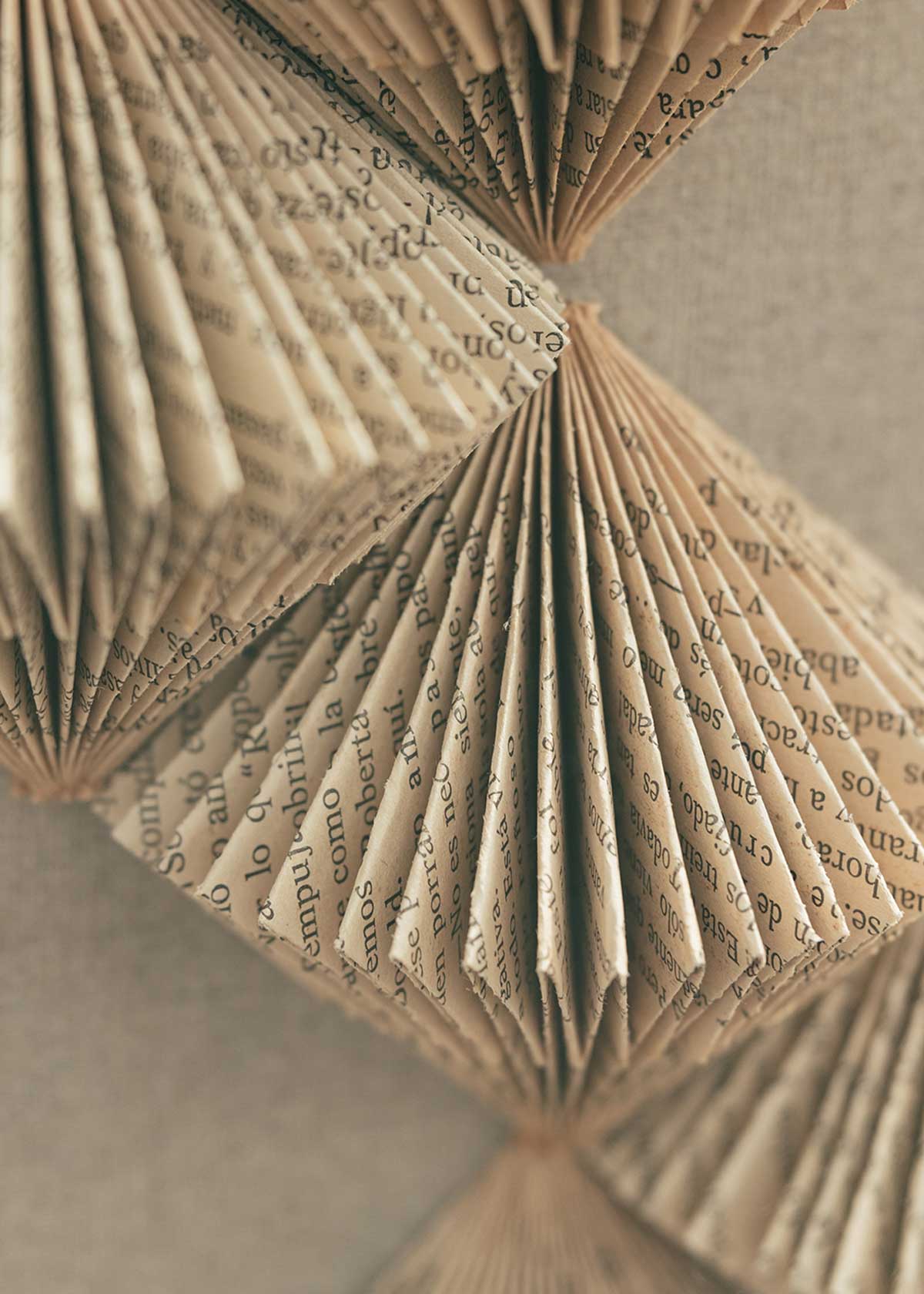 Escultura de pared forrada en lino rústico con caja de metacrilato transparente y serie de libros plegados.