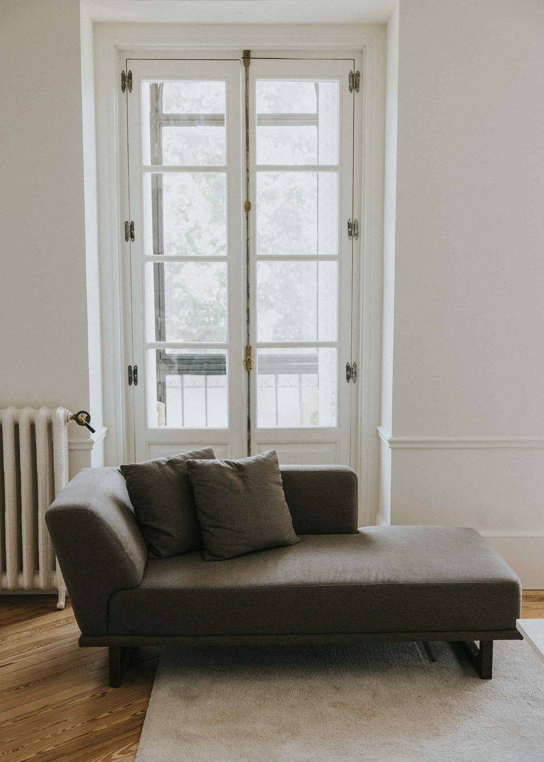 Diván con estructura y patas de madera tapizado con tela gris