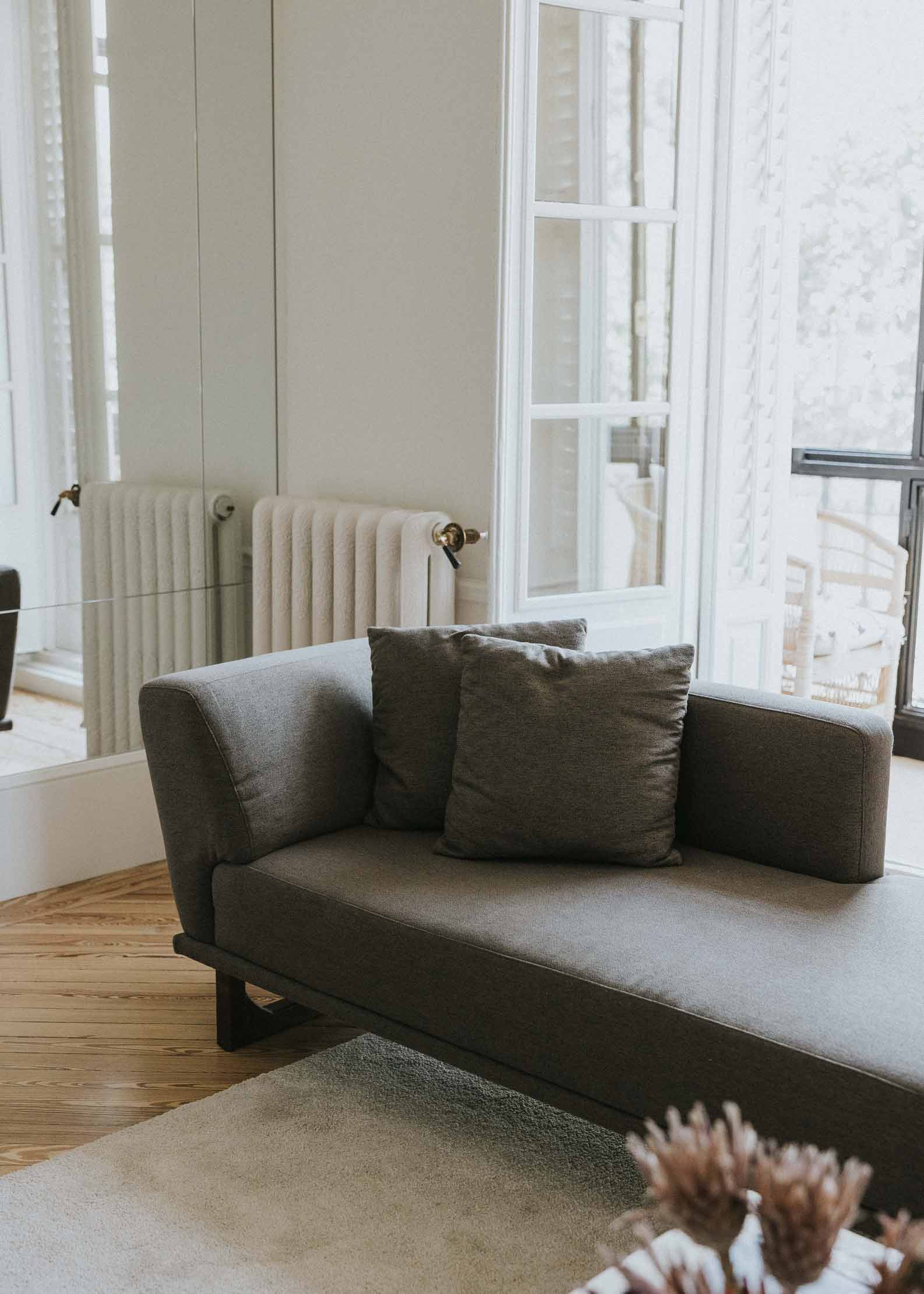 Diván con estructura y patas de madera tapizado con tela gris