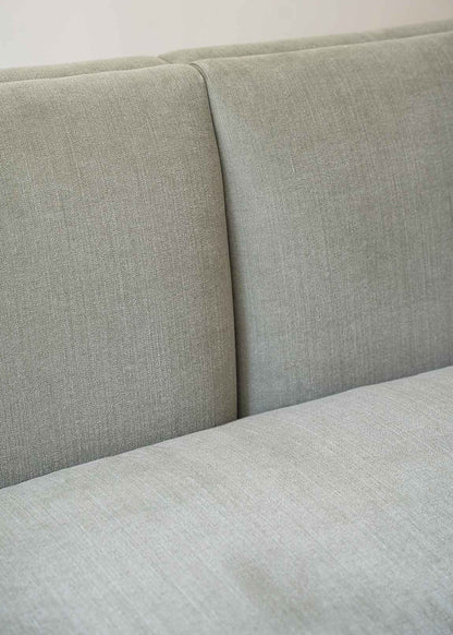 Sofá tapizado en tela gris de lino y algodón con estructura de madera de haya.