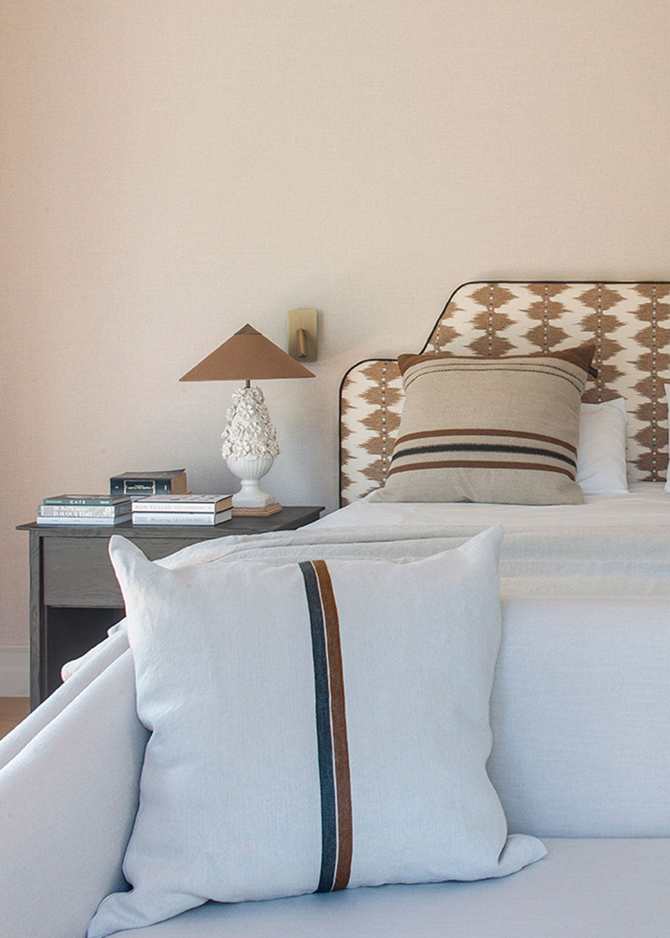 Cabecero tapizado con tela estampada en tonos ocres y crudos.