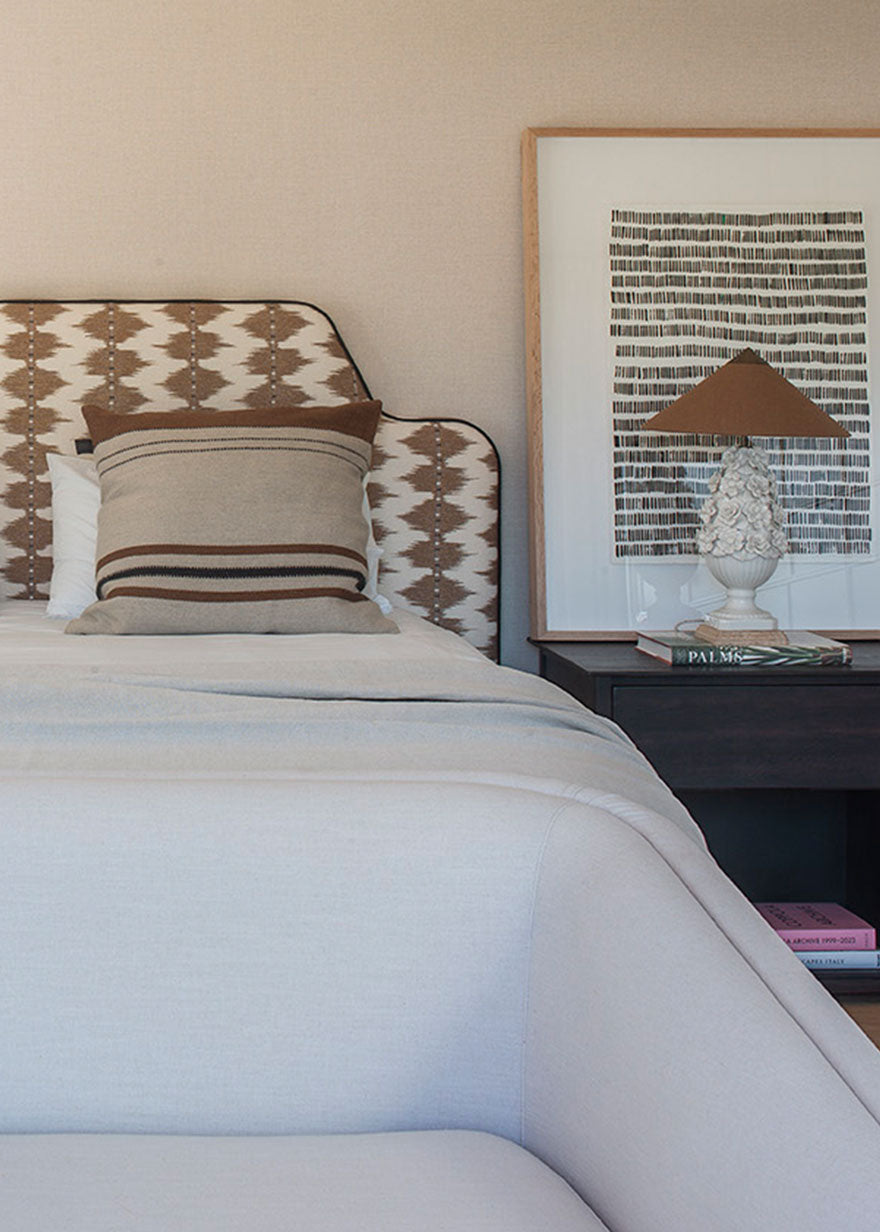 Cabecero tapizado con tela estampada en tonos ocres y crudos.