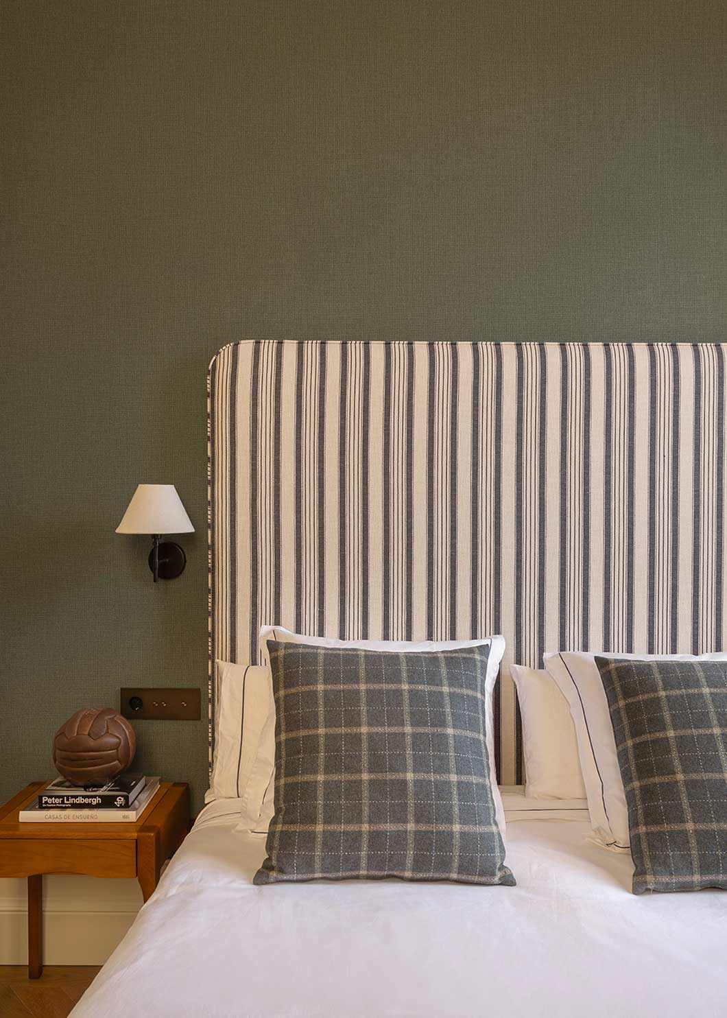 Cabecero individual tapizado en tela estampada de cuadros de rayas.
