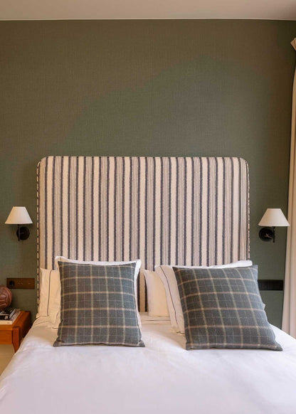 Cabecero individual tapizado en tela estampada de cuadros de rayas.