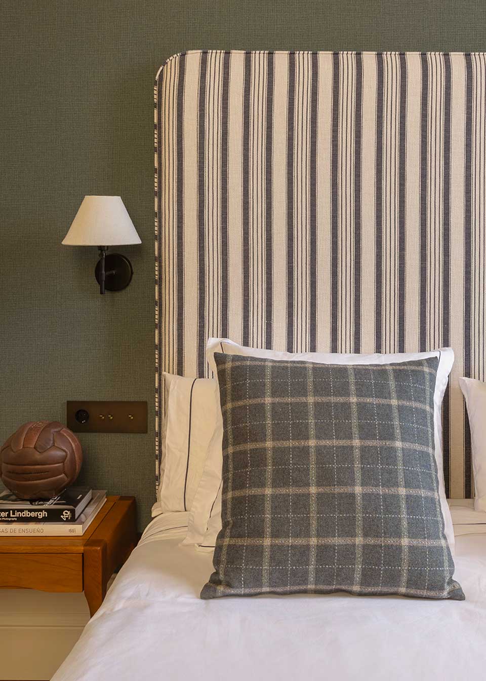 Cabecero individual tapizado en tela estampada de cuadros de rayas.
