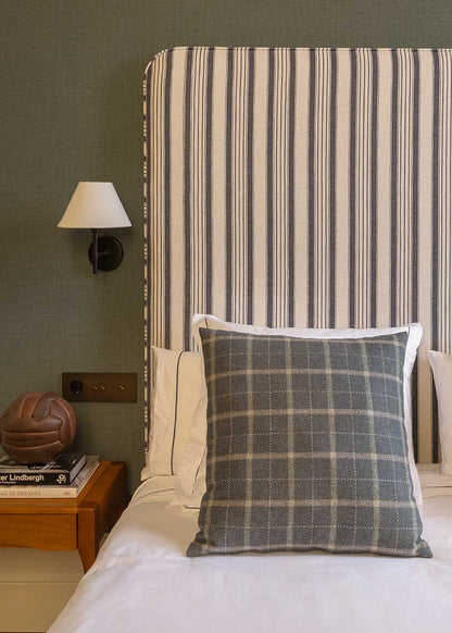 Cabecero individual tapizado en tela estampada de cuadros de rayas.