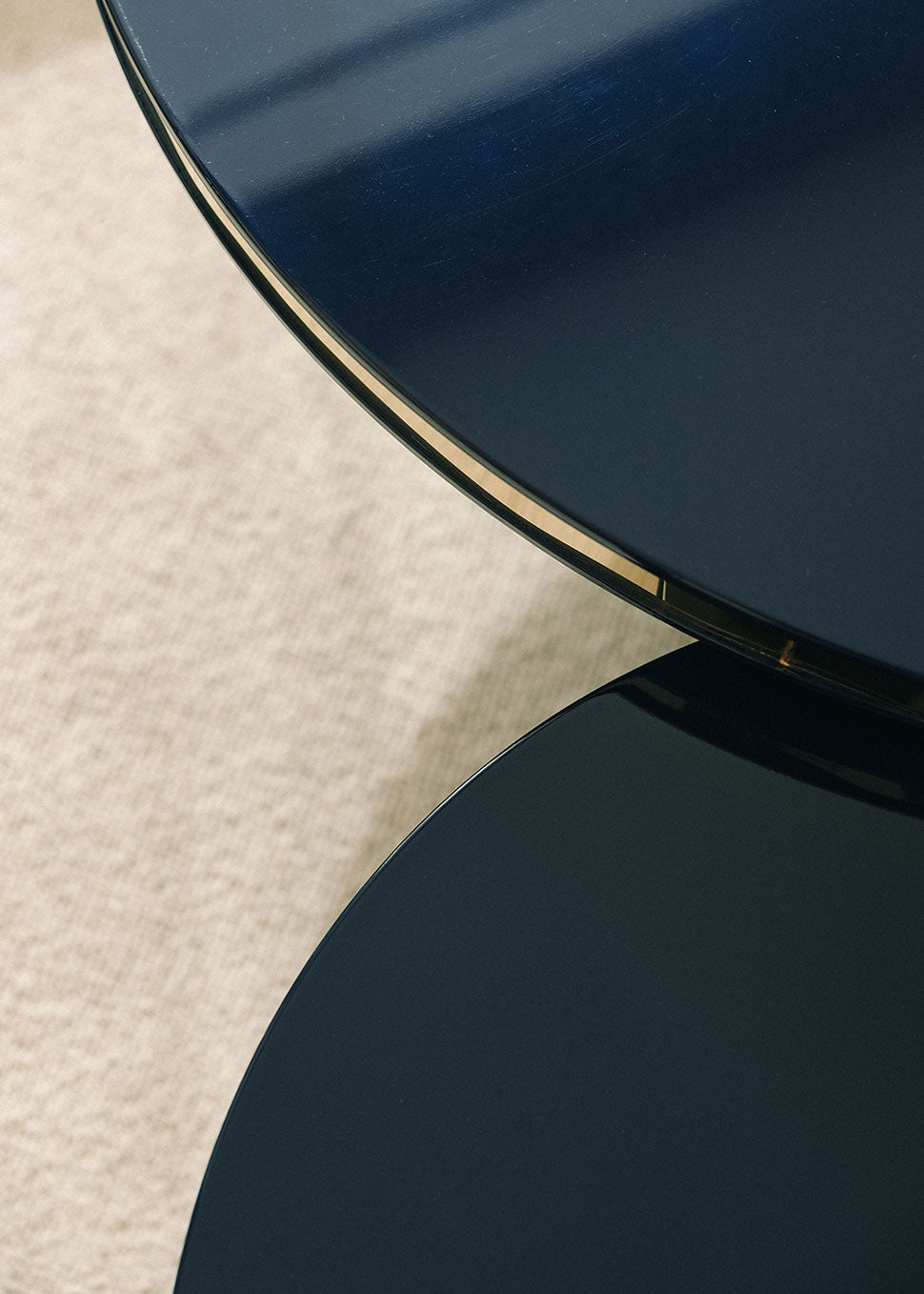 Conjunto de dos mesas circulares realizadas en madera lacadas en color negro con acabado brillo y detalle de latón.