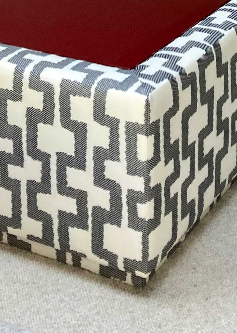 Mesa de centro tapizada con con tela de estampado geométrico y superficie en madera lacada