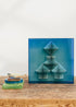 Escultura de pared forrada en lino rústico con caja de metacrilato azul y serie de libros plegados.