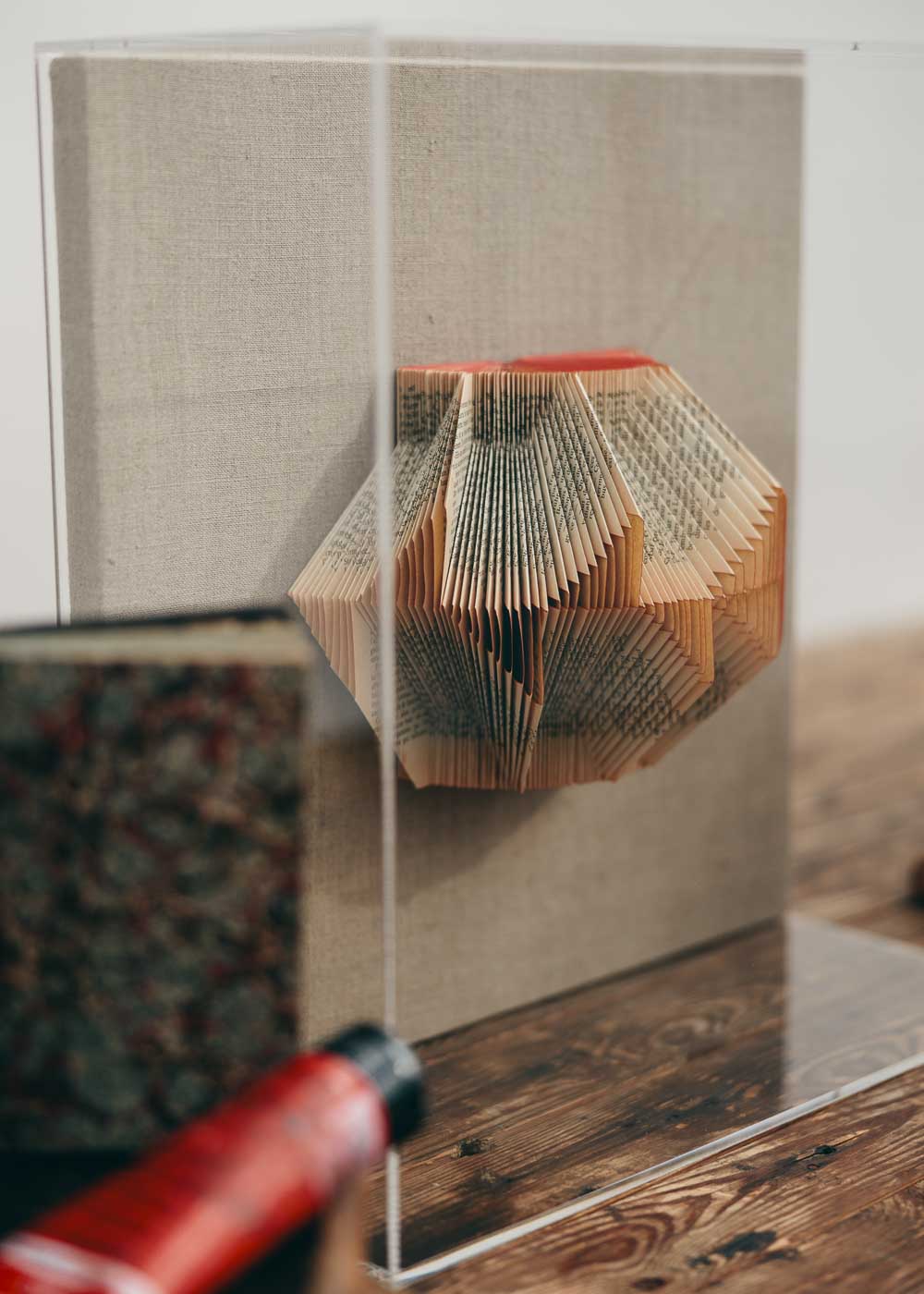 Escultura de pared con caja de metacrilato, forrada en lino y libro plegado