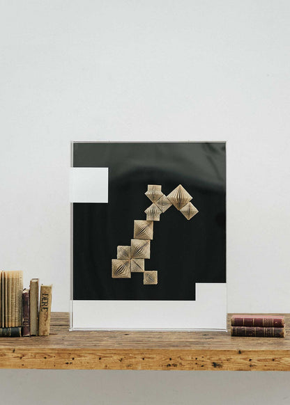 Escultura de pared forrada en metacrilato negro y blanco con caja de metacrilato transparente y serie de libros plegados.