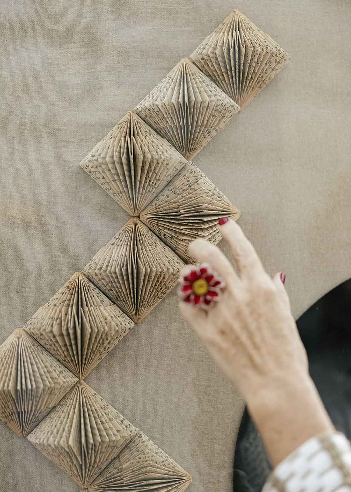 Escultura de pared forrada en lino rústico con caja de metacrilato transparente. Está formada por una serie de libros plegados y formas geométricas en metacrilato.