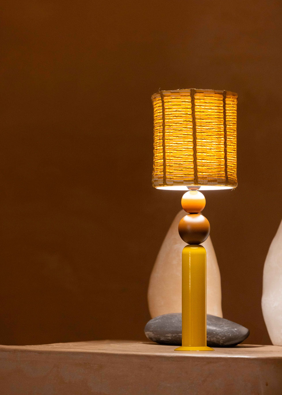 La lámpara N02 tiene el balance perfecto entre diversión y diseño. Su base está diseñada en color mostaza lacada en hierro, combinada con dos bolas de madera lacada en diferentes tamaños, en color arcilla y chocolate.
