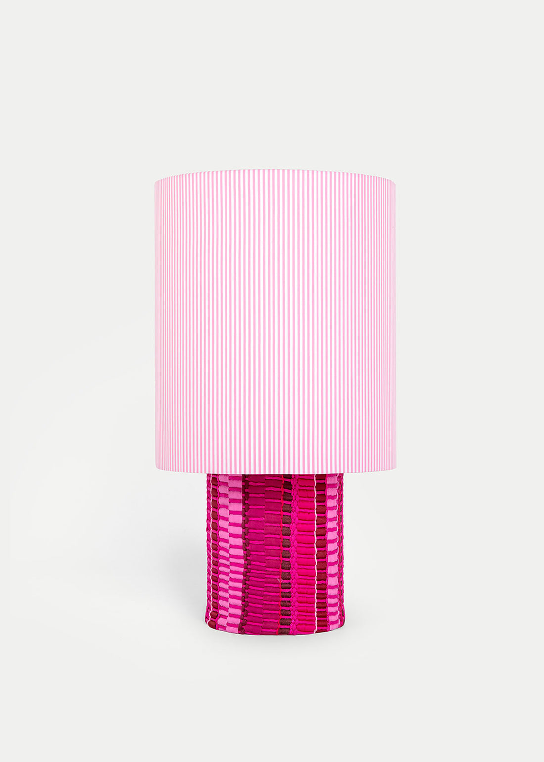 La lámpara N05 es una explosión de color. Perfecta para dar un toque de diversión y diseño a cualquier espacio. Con una base cubierta de tejido hecho en telar, combinando sedas, linos y diferentes texturas y una maxi pantalla de tejido de oxford de rayas rosas.