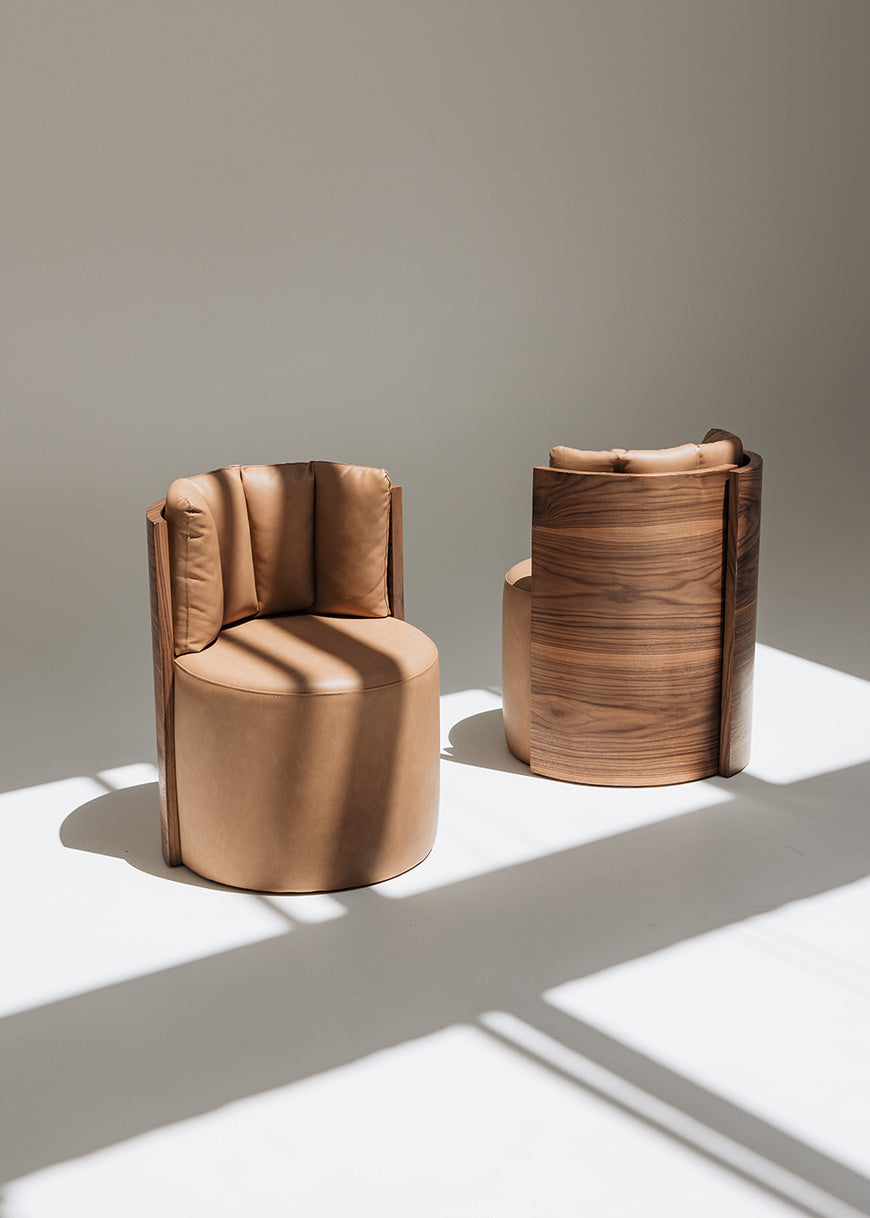 Butaca redonda con estructura de madera tapizada en dos telas, una de color beige para el asiento y una tela una polipiel camel para el respaldo.