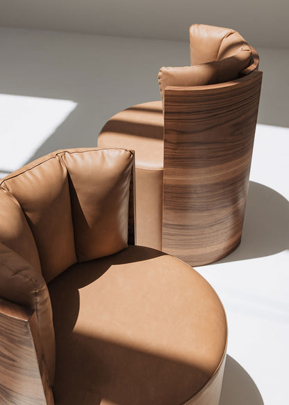 Butaca redonda con estructura de madera tapizada en dos telas, una de color beige para el asiento y una tela una polipiel camel para el respaldo.