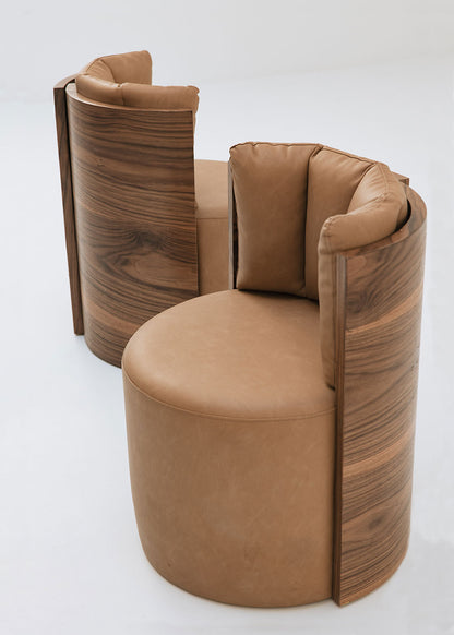 Butaca redonda con estructura de madera tapizada en dos telas, una de color beige para el asiento y una tela una polipiel camel para el respaldo.