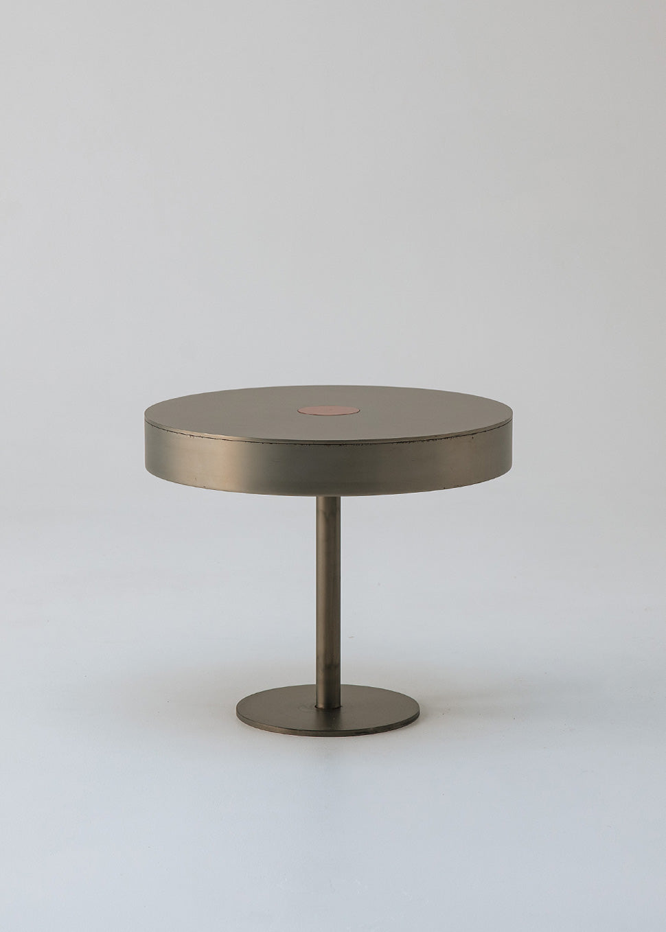 Mesa circular de centro realizada en acero con acabado mate y detalle lacado en rojo en el centro.