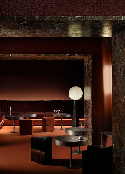 Mesa circular de centro realizada en acero con acabado mate y detalle lacado en rojo en el centro.