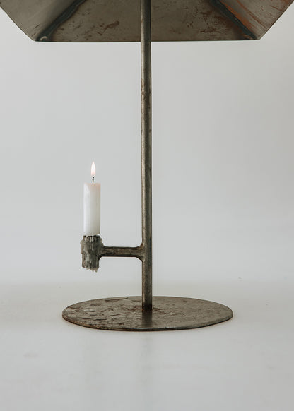 Portavelas metálico con forma de lámpara.