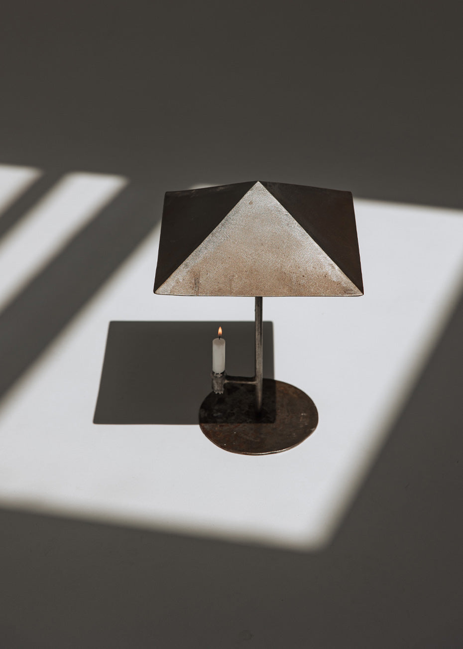 Portavelas metálico con forma de lámpara.