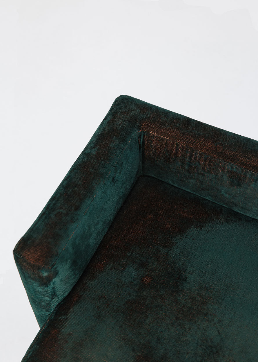 Puf cuadrado tapizado en terciopelo azul con detalle de flecos en la parte inferior.