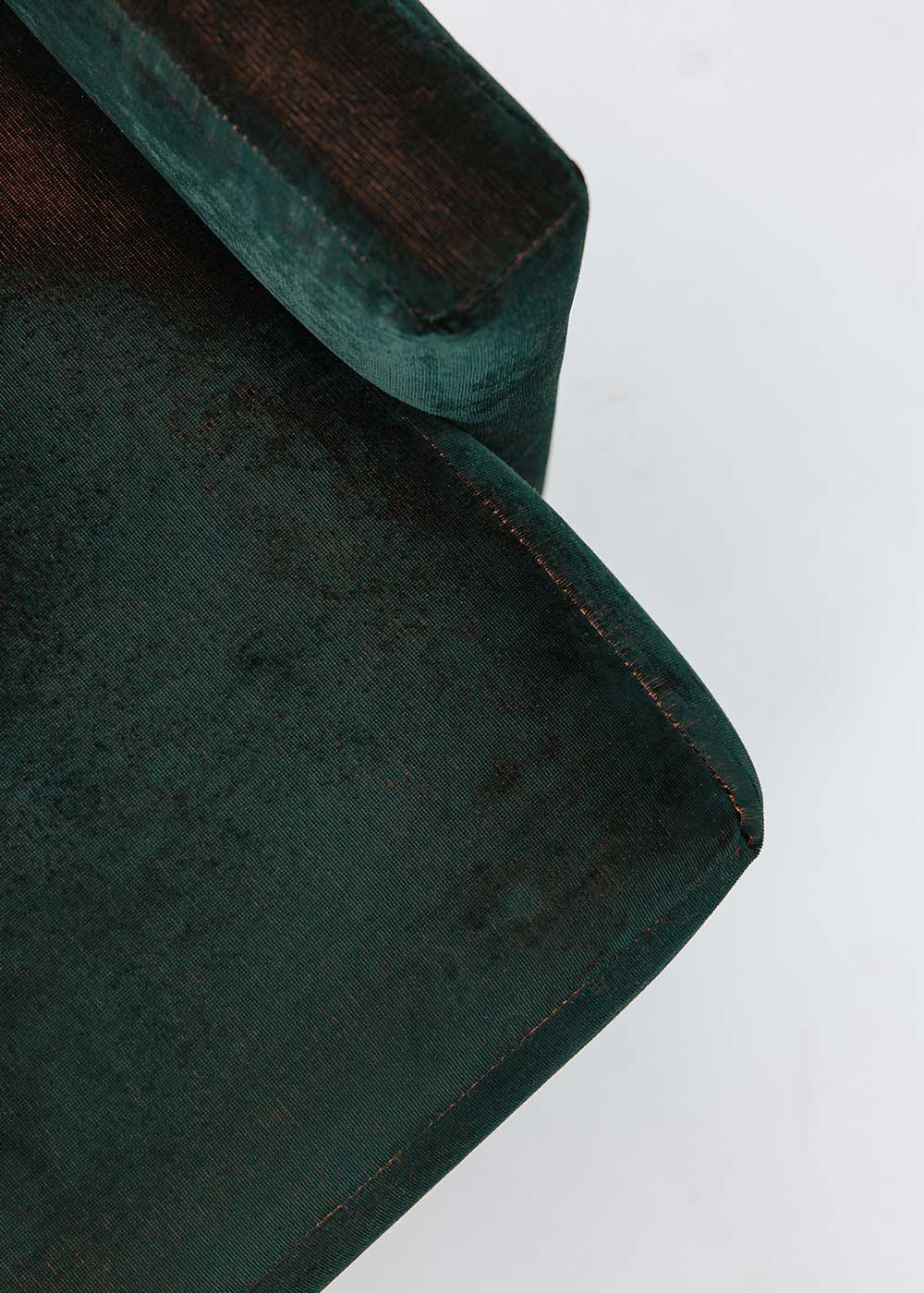 Puf cuadrado tapizado en terciopelo azul con detalle de flecos en la parte inferior.