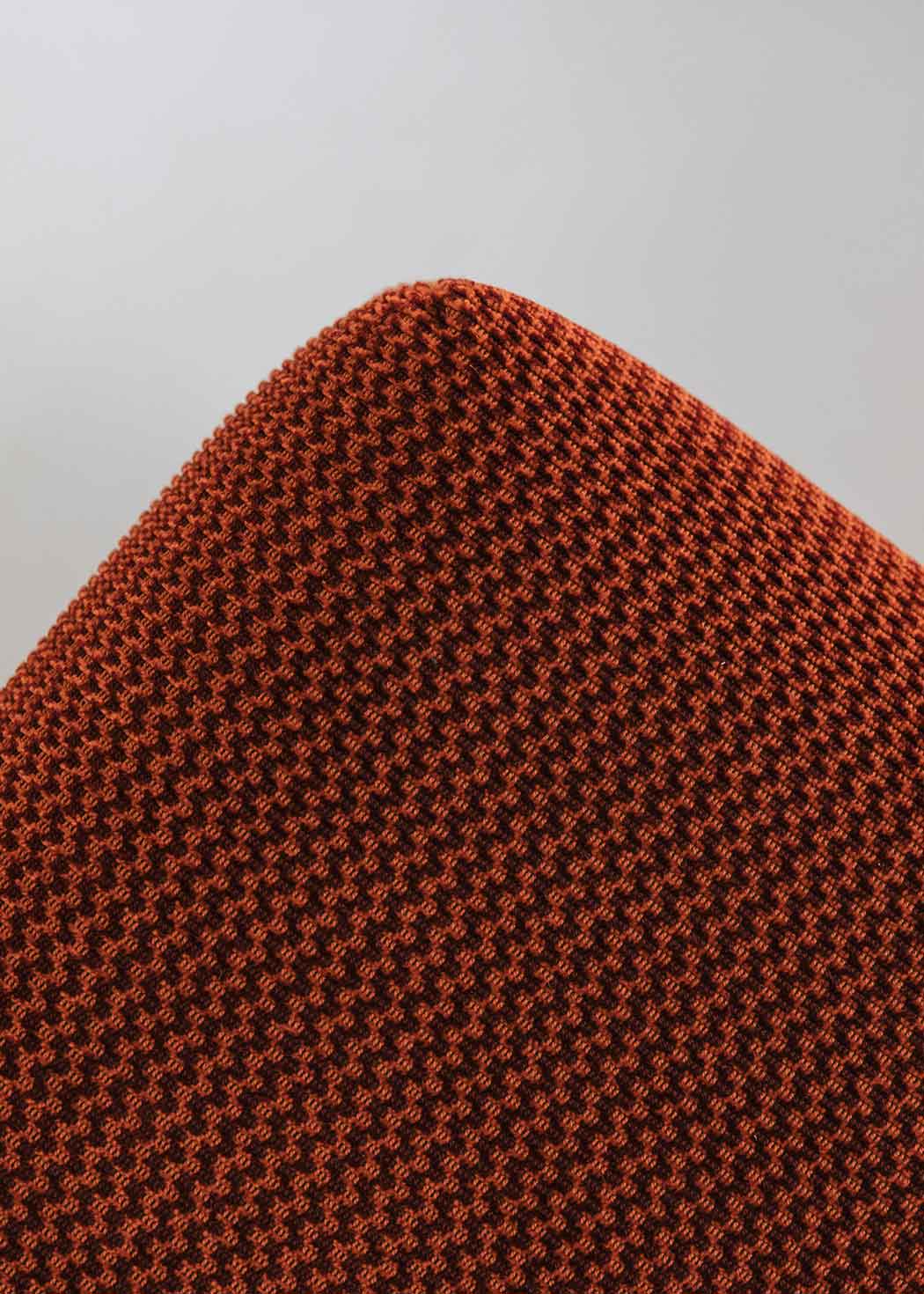 Puf cuadrado tapizado en terciopelo rojo con remates laterales de acero inoxidable.