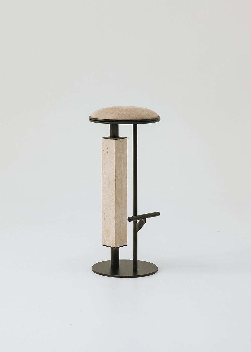 Taburete tapizado con estructura de hierro con detalle de piedra travertino. Un taburete alto con reposapiés y asiento tapizado en tela de terciopelo beige.