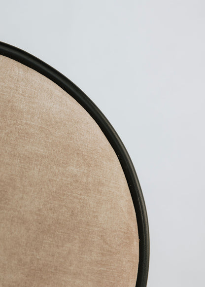 Taburete tapizado con estructura de hierro con detalle de piedra travertino. Un taburete alto con reposapiés y asiento tapizado en tela de terciopelo beige.