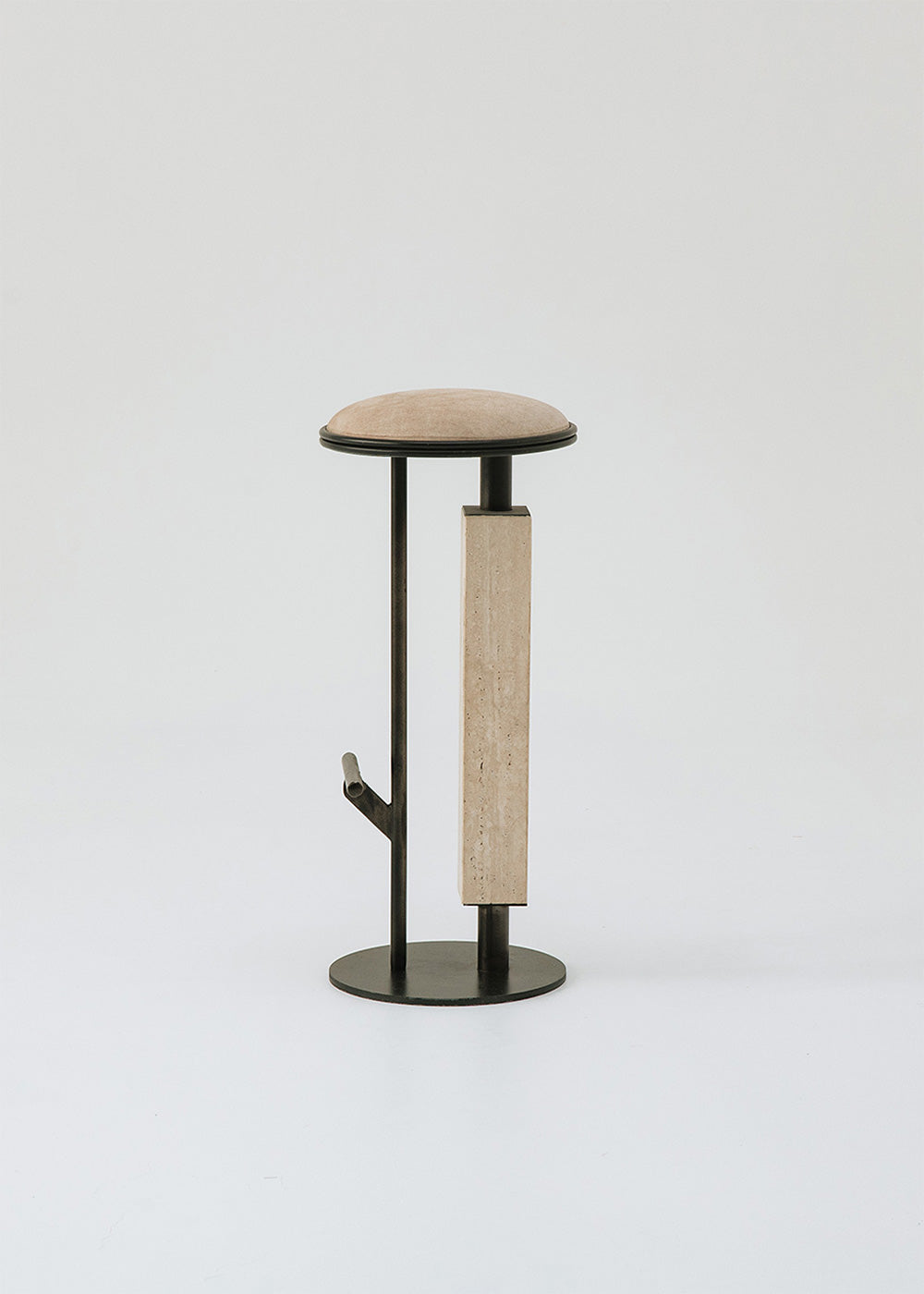 Taburete tapizado con estructura de hierro con detalle de piedra travertino. Un taburete alto con reposapiés y asiento tapizado en tela de terciopelo beige.