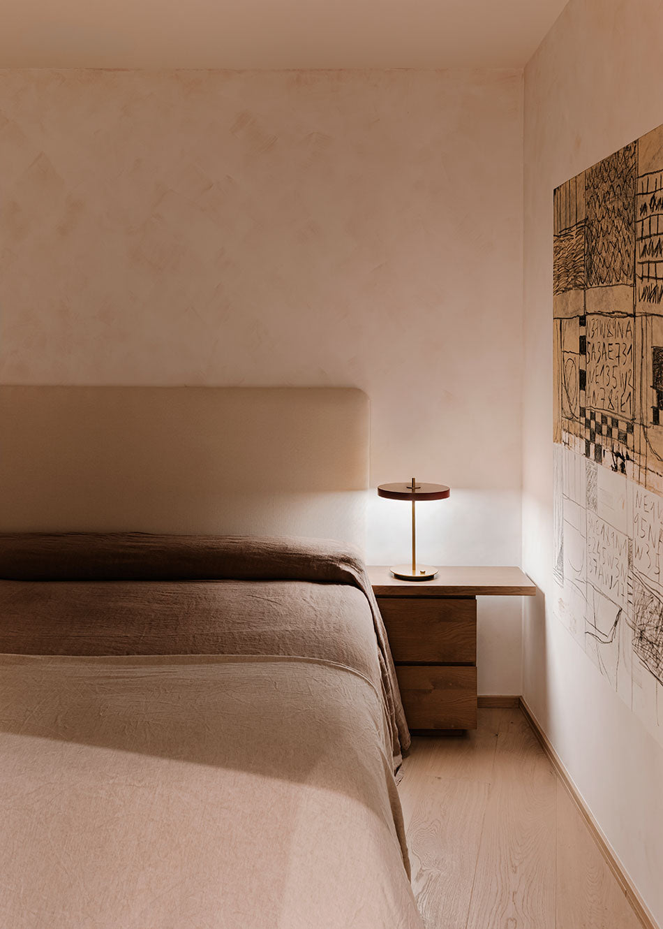 Cabecero tapizado en tela color topo con forma rectangular.