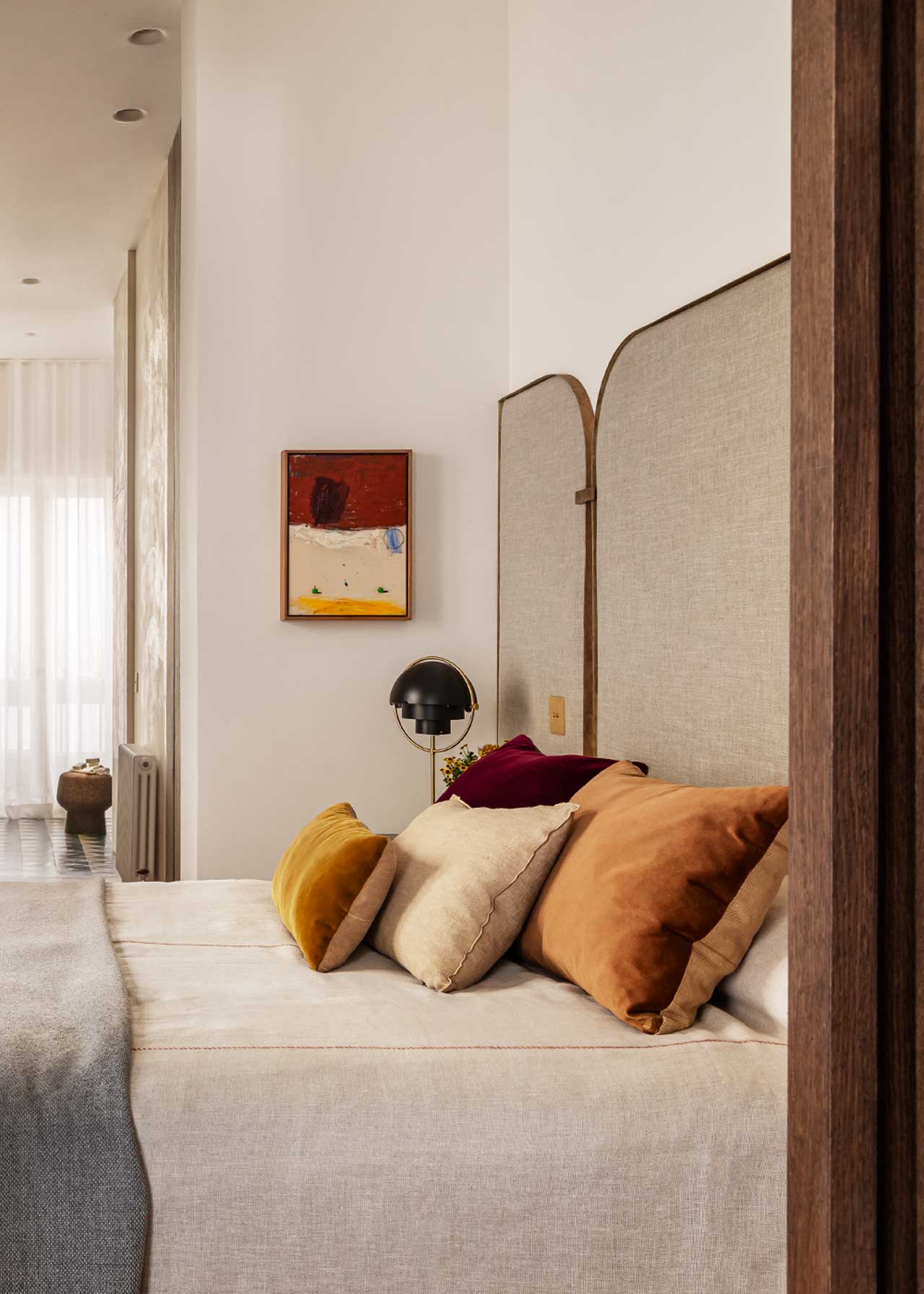 Cabecero tapizado en tela color topo en forma de tríptico con esquinas redondeadas y bordes en chapa envejecida.