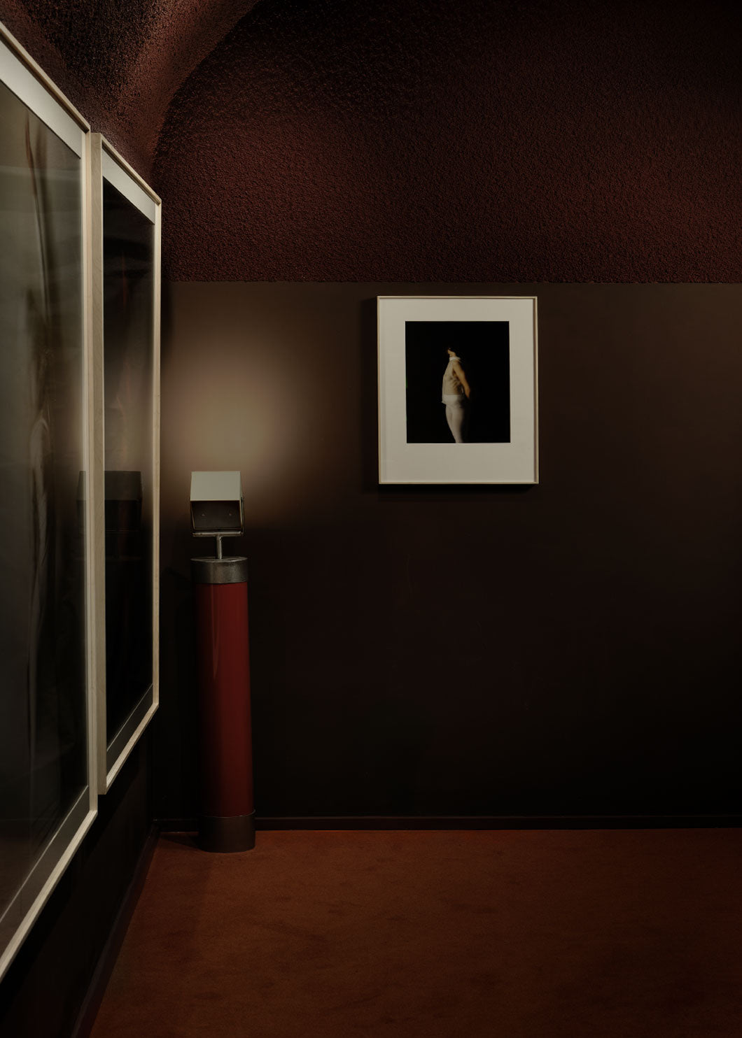 Foco orientable de pie de estilo industrial con soporte de acero lacado en rojo. Está diseñado para ir anclado al suelo.