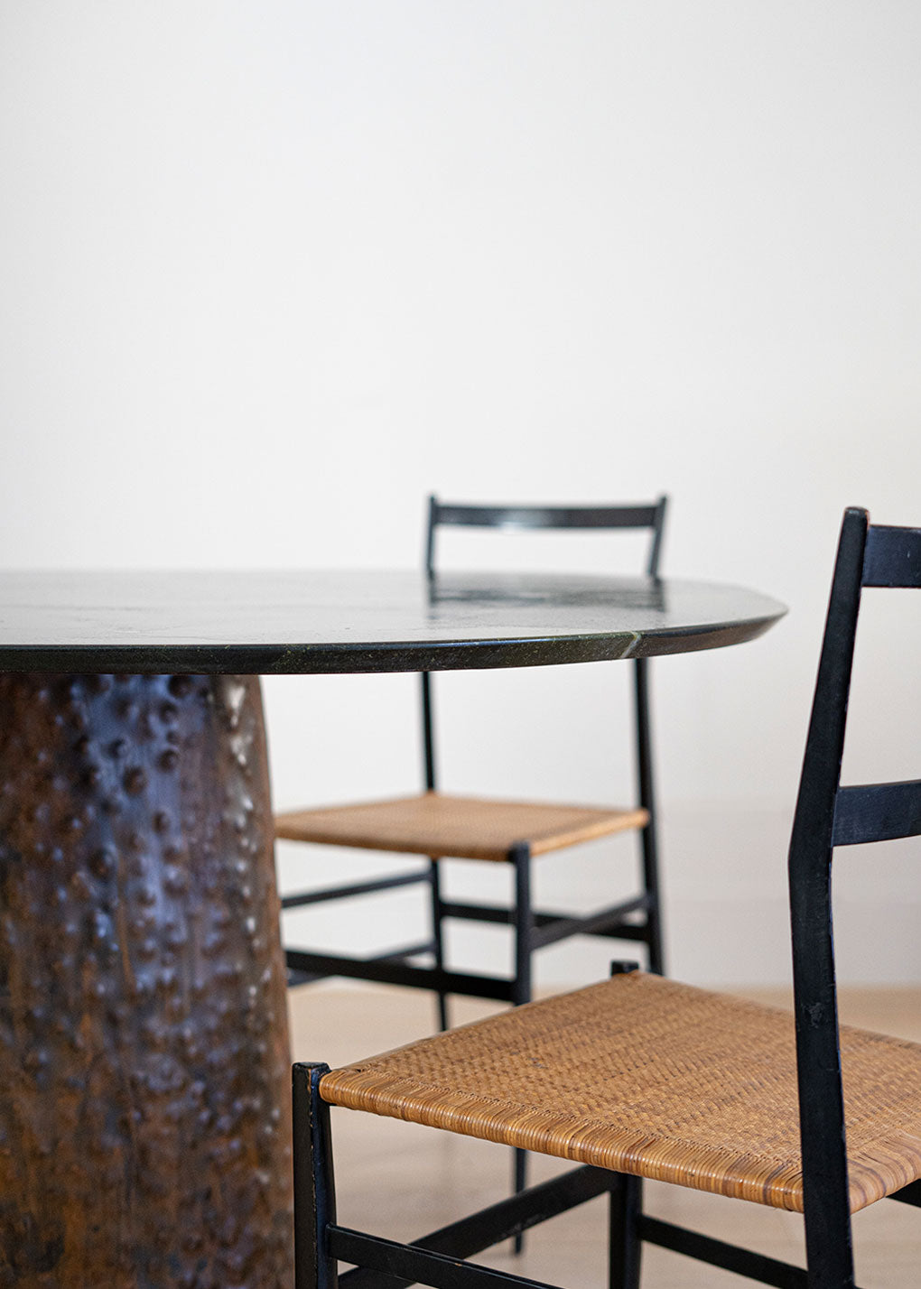 Mesa de comedor de cuarcita Avocatus con borde en pico de flauta y pie de metal oxidado con acabado martilleado y capa protectora.