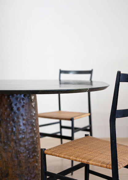 Mesa de comedor de cuarcita Avocatus con borde en pico de flauta y pie de metal oxidado con acabado martilleado y capa protectora.