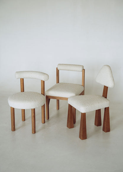 Silla de madera de haya tapizada en bouclé blanco con respaldo semicircular.
