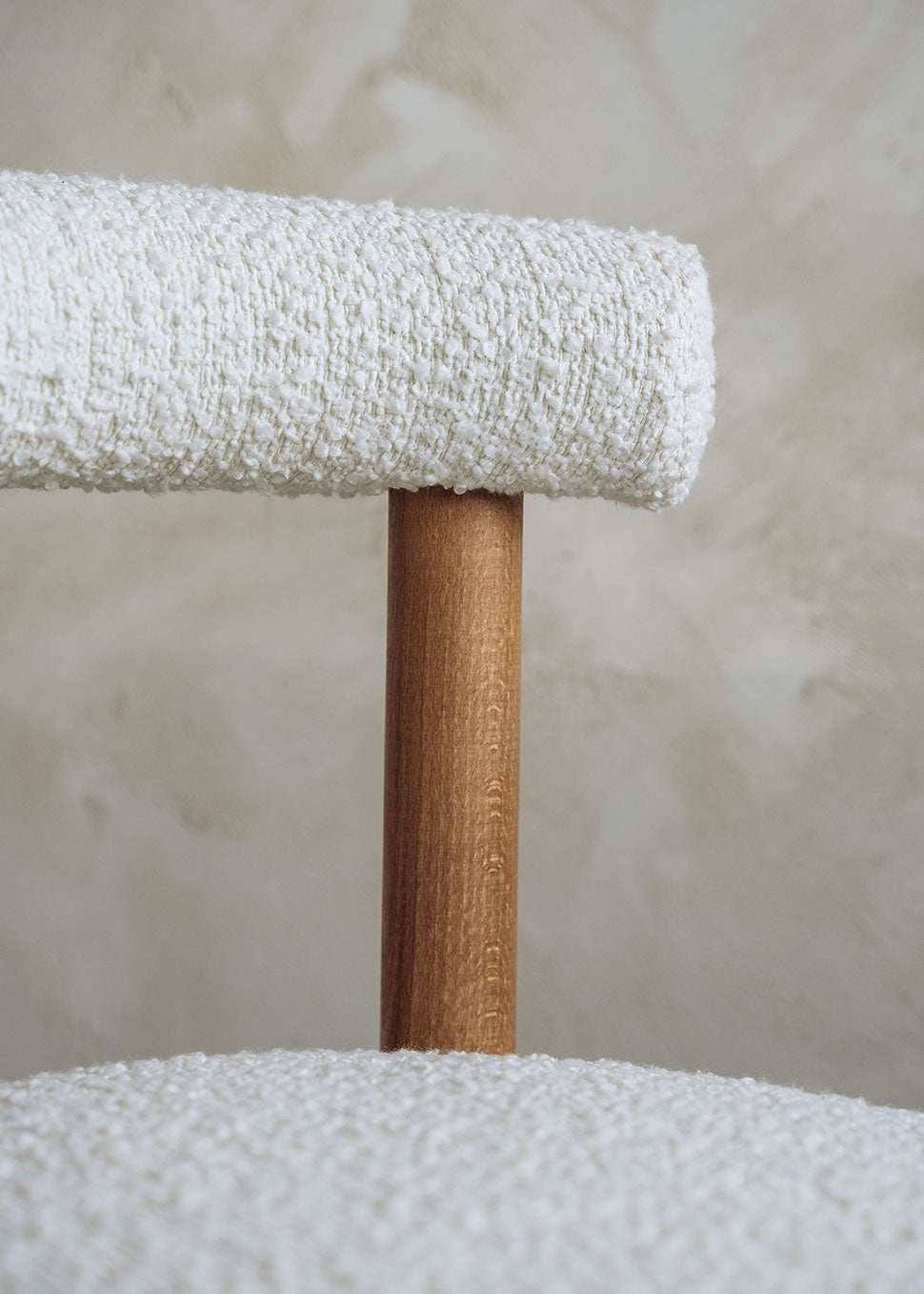 Silla de madera de haya tapizada en bouclé blanco con respaldo semicircular.